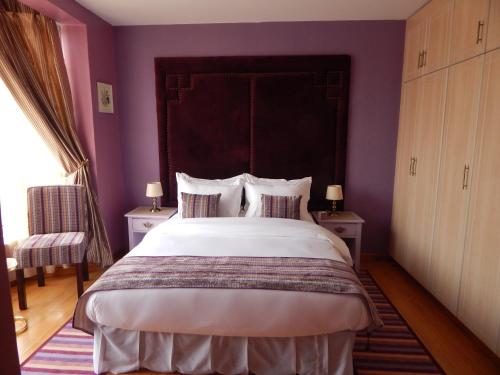a bedroom with a large bed with purple walls at Salmiya Place in Nairobi