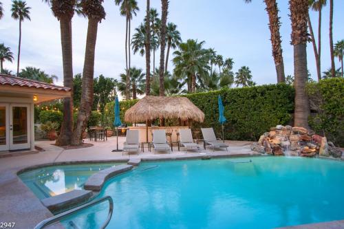 a swimming pool with chairs and a gazebo and palm trees at Maison du Soleil in Palm Springs