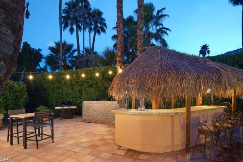 a patio with a table and a straw umbrella at Maison du Soleil in Palm Springs