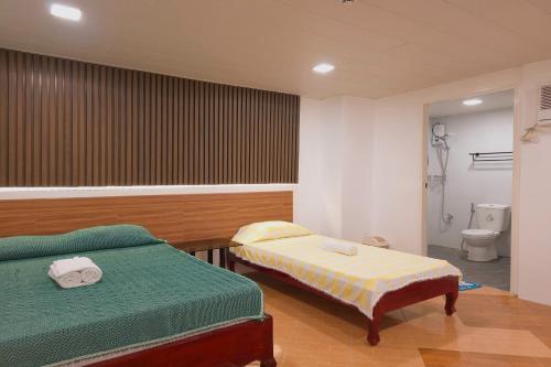 a bedroom with two beds and a bathroom with a toilet at Green Meadows Hotel & Restaurant in San Nicolas