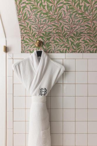 a white dress hanging on a rack in a bathroom at Bradford House, a Member of Design Hotels in Oklahoma City