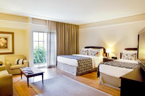 a hotel room with two beds and a couch at Royal Palm Plaza Resort in Campinas