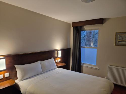 a hotel room with a bed and a window at Woodside House in Aberdeen