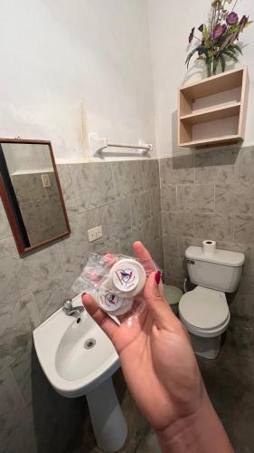 una persona che tiene una macchina fotografica in un bagno di Posada Colonial 