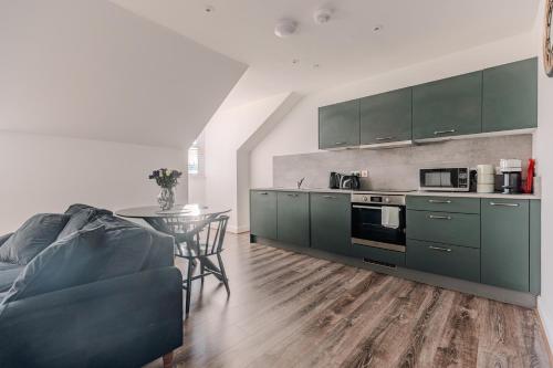a kitchen with green cabinets and a table at Barnet House Serviced Apartments in Dunfermline