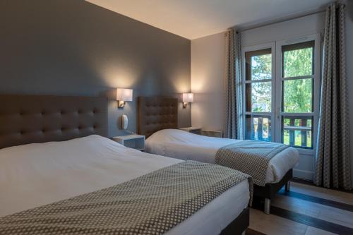 a hotel room with two beds and a window at Hotel Village Motel in Tournus