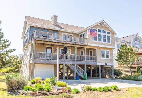 a house with an american flag in front of it at Shore Enough - Duck, Sanderling, 50 Yds to Beach, Elevator, Pets OK, Community Pool, Flex Stays in Duck