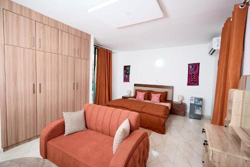 a bedroom with a bed and a couch at La Villa Tombouctou in Bingerville