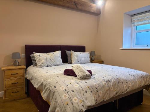 a bedroom with a bed with two pillows and a window at The Cow 'ouse, Wolds Way Holiday Cottages, 1 bed cottage in Little Weighton