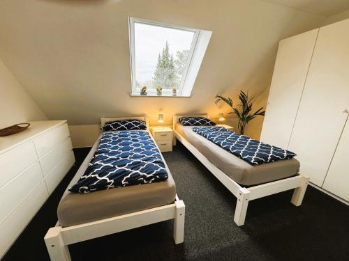 two beds in a small room with a window at Business-Apartment Ahrensburg in Ahrensburg