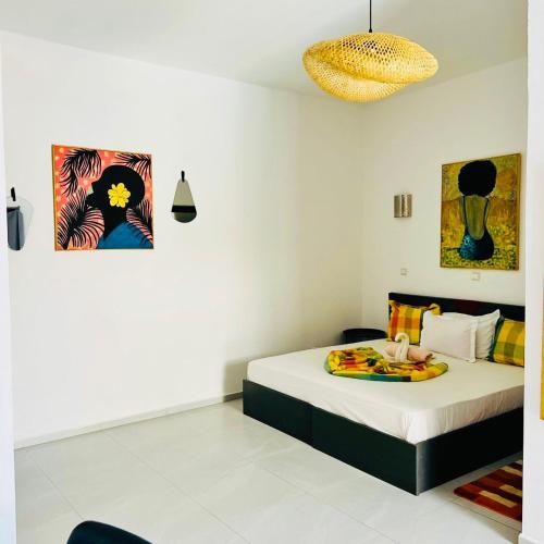 a bedroom with a bed and two paintings on the wall at La Brise de Ngaparou in Ngaparou