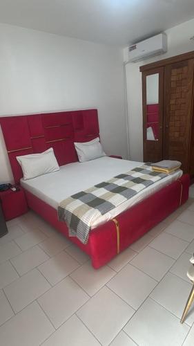ein Bett mit rotem Kopfteil in einem Zimmer in der Unterkunft Résidence OUZA in Dakar