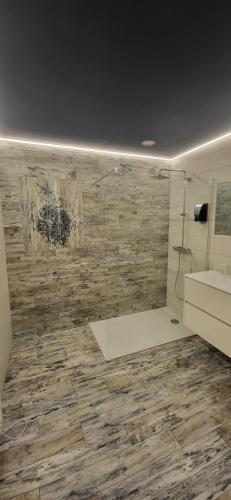 a bathroom with a shower and a stone wall at American spa motel in Joncherey