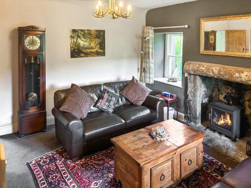 a living room with a leather couch and a fireplace at Professors Cottage in Girvan