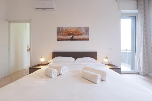 a white bedroom with a white bed with two white towels at Primopiano - Olgettina in Vimodrone