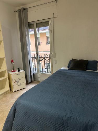 a bedroom with a blue bed and a balcony at Habitación individual in Madrid