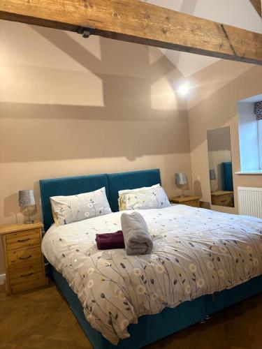 a bed with a blue headboard in a bedroom at The Milking Parlour, Wolds Way Holiday Cottages, 1 bed cottage in Cottingham