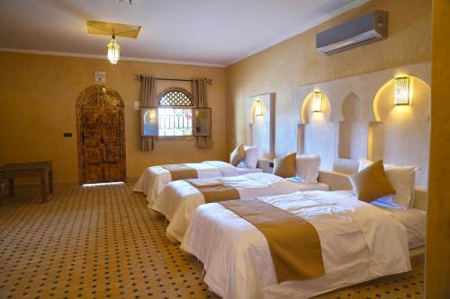 a group of four beds in a room at Hotel Sunset Palace in Merzouga