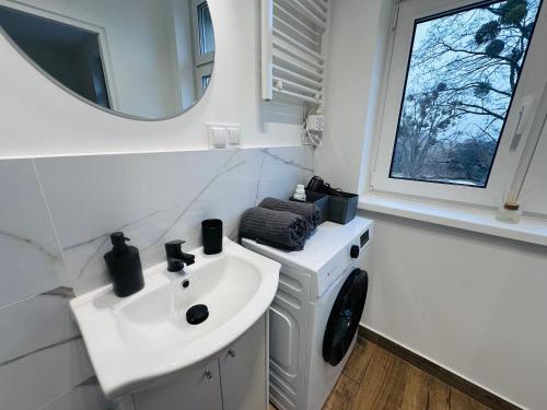 a white bathroom with a sink and a mirror at Apartamenty przy Galerii in Kluczbork