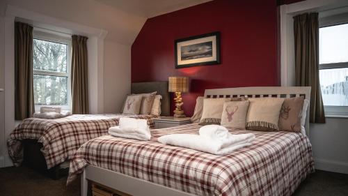 a bedroom with two beds with red walls at Burnside, Dornoch in Dornoch