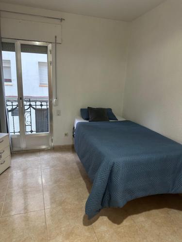 a bedroom with a blue bed and a window at Habitación individual in Madrid