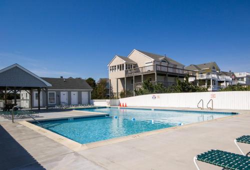 a swimming pool with chairs and houses in the background at Dolphin's Song -Corolla, Villages at Ocean Hill, 350 Yds to Beach, Pets OK, Hot Tub, Community Pools in Corolla