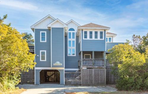 a large blue house with a gate in front of it at Dolphin's Song -Corolla, Villages at Ocean Hill, 350 Yds to Beach, Pets OK, Hot Tub, Community Pools in Corolla