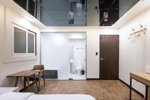 a room with a bed and a table and a toilet at Lien Hotel Haeundae in Busan
