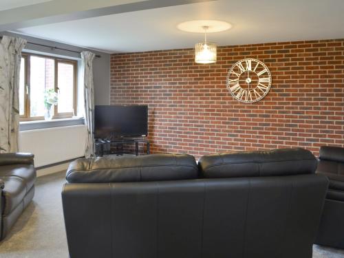 a living room with a couch and a brick wall at Carp Cottage - Ukc1907 in Doddington
