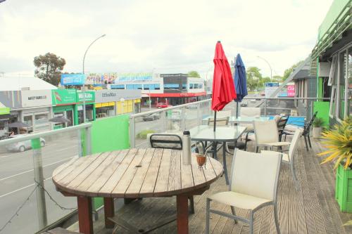 a patio with tables and chairs and umbrellas on a roof at Backpackers Central Hamilton in Hamilton