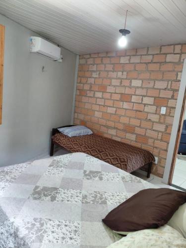 a bedroom with two beds and a brick wall at POUSADA Botos de Alter quarto compartilhado in Alter do Chao