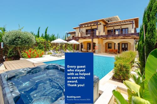 a sign in front of a house with a swimming pool at Luxury Elite Villa AJ06 complete with a private, climate controlled pool and a relaxing outdoor Jacuzzi, Aphrodite Hills Resort in Paphos