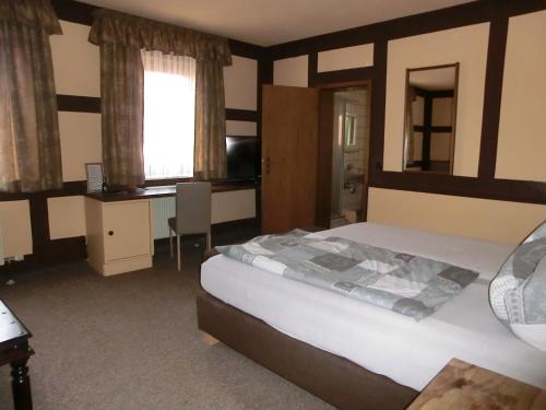 a bedroom with a bed and a desk and window at Hotel Glindenberger Hof in Glindenberg