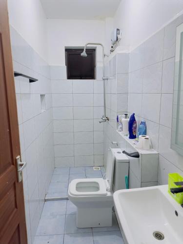 a white bathroom with a toilet and a sink at Diani Beach Modern Apartment in Diani Beach