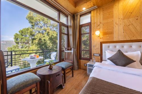 a bedroom with a bed and a balcony with a view at Whispering Woods Homestay Kasauli !! in Kasauli