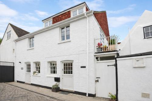 a white house with a balcony on a street at Stylish Cottage with Quay and River View in Lymington