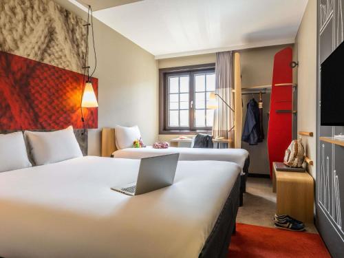 a hotel room with two beds and a laptop on a desk at ibis Hotel Brussels off Grand'Place in Brussels