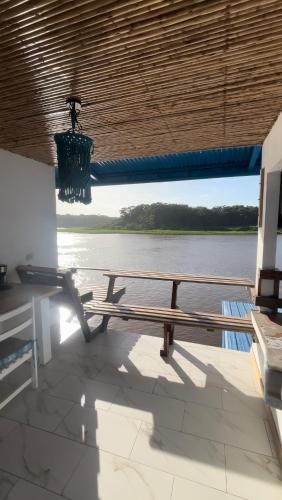 a bench sitting under a roof with a view of the water at Hotel Pura Natura Riverside Tortuguero in Tortuguero