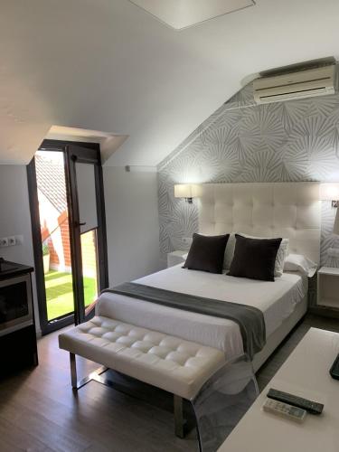 a bedroom with a large white bed with a bench at Hostal el Rocio in Paracuellos de Jarama