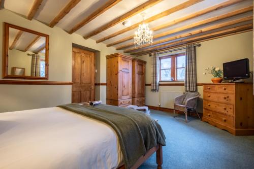 a bedroom with a bed and a tv and a dresser at Smithy Cottage in Hawkshead
