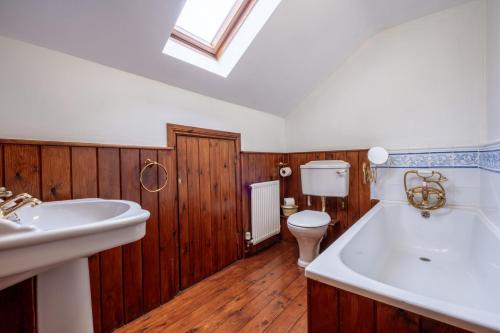 a bathroom with a tub and a toilet and a sink at Smithy Cottage in Hawkshead