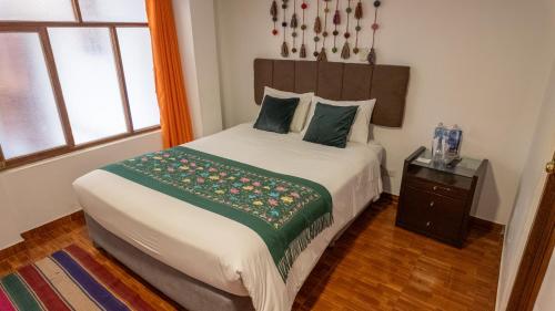 a bedroom with a large bed with a green blanket at Munay Ñusta Cusco in Cusco