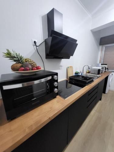 a kitchen with a microwave and a bowl of fruit on a counter at Quarto individual perto de Lisboa e Sintra in Queluz