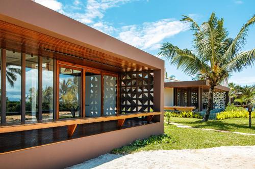a house on the beach with a palm tree in the background at Alma Maraú - Praia do Cassange in Marau
