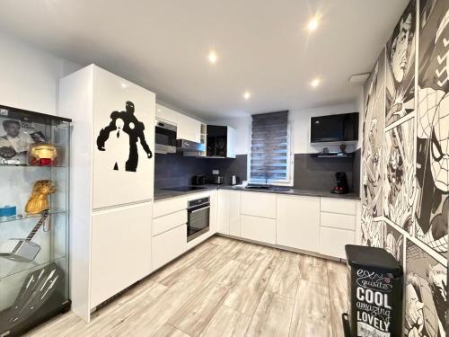 a kitchen with white cabinets and a black and white wall at Disney Avengers House in Magny-le-Hongre