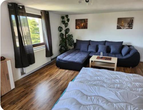 a living room with a blue couch and a bed at Gästewohnung Rauw in Saint-Vith