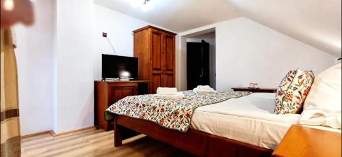 a bedroom with a bed and a flat screen tv at Pensiunea Restaurant Vándor in Cîmpu Cetăţii