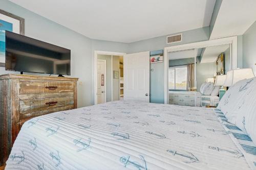 a bedroom with a large bed and a flat screen tv at Plantation Palms 6305 in Gulf Highlands