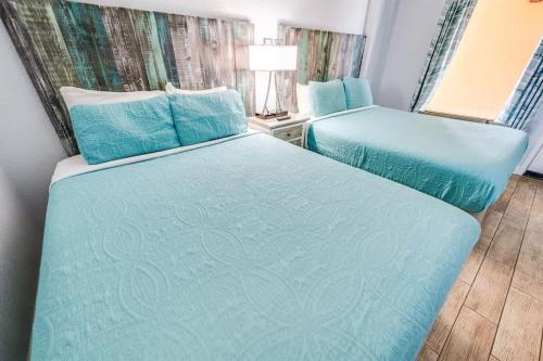 two beds in a small room with blue sheets at Prime Ocean Frontage The Pavilion in Myrtle Beach