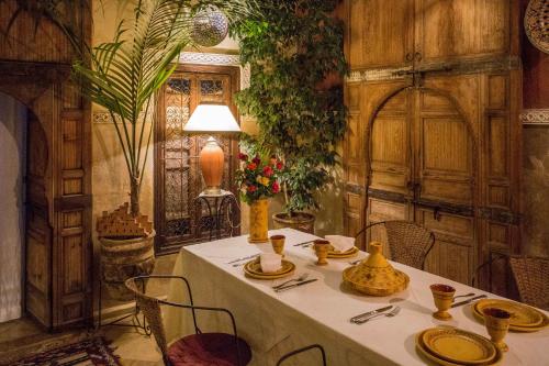 a table with a white table cloth and chairs in a room at Riad Light Of Sun in Marrakech